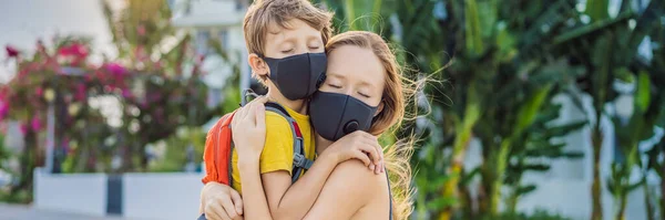 mom hugs a sad son on the sidewalk in the city. Mother and baby wear face mask during coronavirus and flu outbreak. Protection against viruses and diseases, quarantine period BANNER, LONG FORMAT