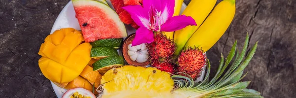 Kleurrijke tropische vruchten op grote schaal. Op rustieke houten ondergrond. Bovenaanzicht BANNER, LANG FORMAT — Stockfoto