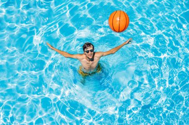 Adam plaj topuyla havuzda oynuyor.