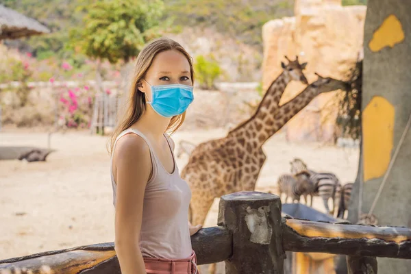 Young woman at the zoo in a medical mask. Visiting public places after the coronavirus epidemic — Stock Photo, Image