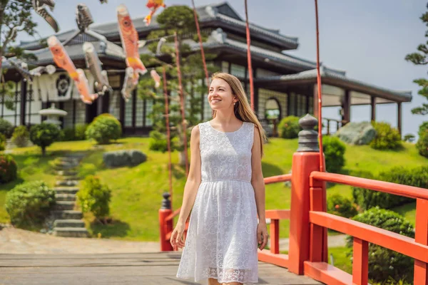 旅行者は通りに立ち、日本の伝統的な建物を見ていました。日本は路地で京都ショッピングで休暇中の観光客の女性を旅行します。陽気に日本を訪問 — ストック写真