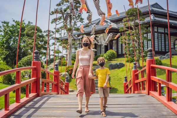 Viajantes de mãe e filho em máscara médica pararam na rua e olhando para o edifício tradicional japonês. Turistas viajam no Japão após a epidemia de coronavírus — Fotografia de Stock