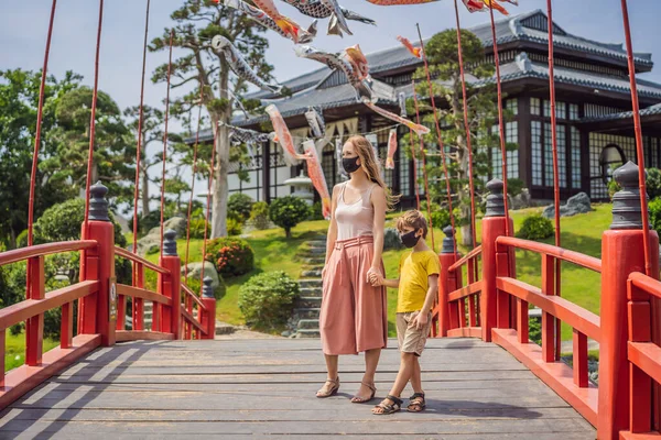 의료용 마스크를 쓴 어머니와아 들 이 거리에 멈춰서 서 일본 전통 건물을 구경하고 있었다. 코로나 바이러스가 유행 한 이후 관광객들 이 일본으로 여행하다 — 스톡 사진