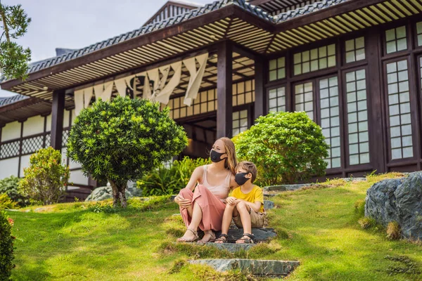 Reizigers van moeder en zoon met een medisch masker stopten op straat en keken naar het Japanse traditionele gebouw. Toeristen reizen in Japan na de coronavirusepidemie — Stockfoto