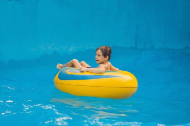 Havuzda yüzen çocuk su parkında yapay dalgalarda yüzüyor.
