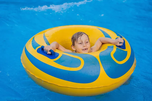 Menino em uma piscina flutuar em ondas artificiais em um parque aquático — Fotografia de Stock