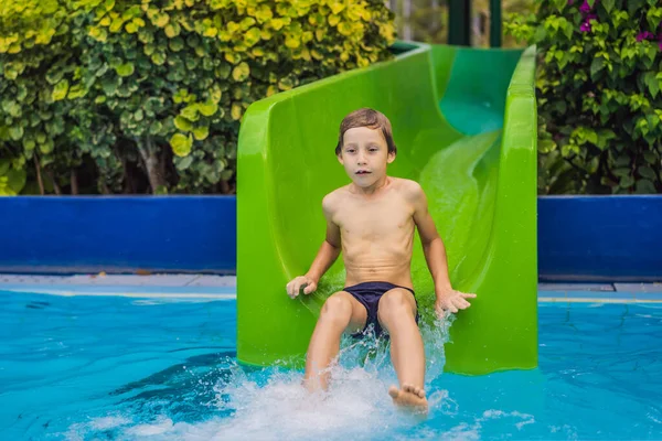 Mladý chlapec nebo dítě se baví cákání do bazénu po sesuvu vody během léta — Stock fotografie