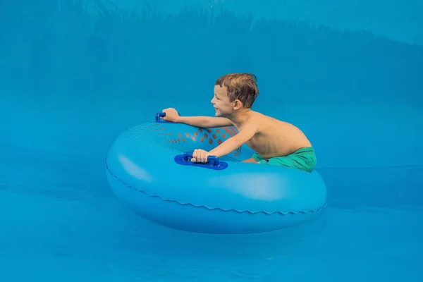 Мальчик на бассейне плавает на искусственных волнах в аквапарке — стоковое фото