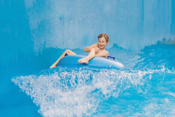 Menino em uma piscina flutuar em ondas artificiais em um parque aquático — Fotografia de Stock