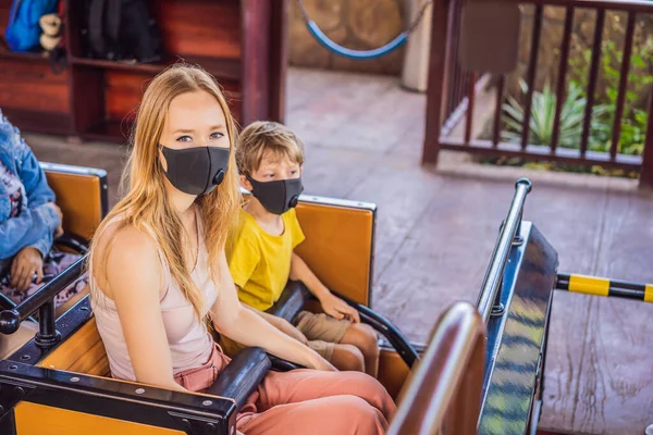 Mom and son on a roller coaster in medical masks after the coronovirus epidemic COVID 19 — Stock Photo, Image