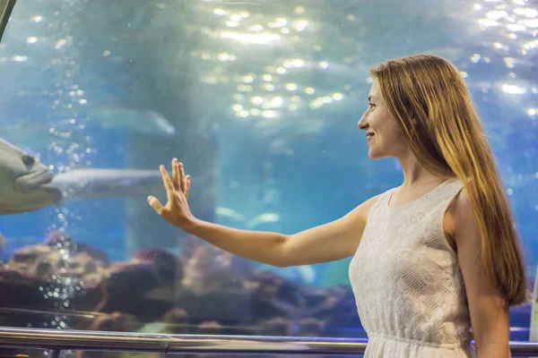 Een jonge vrouw raakt een pijlstaartrog vis in een oceanarium tunnel aan — Stockfoto