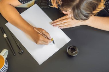 Mokup, Sahne Tasarımcısı Genç Kadın beyaz kağıda cümleler yazıyor. Süslü harfleri kazıyarak. Kaligrafi, grafik tasarım, harf, el yazısı, yaratım konsepti