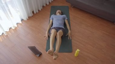 Tabletten izlediği bir videoda talimatları takip eden genç bir adam evde fiziksel egzersiz yapıyor. Sosyal uzaklık kavramı. İnternet çalıştırıcı kavramı