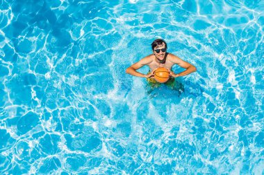 Adam plaj topuyla havuzda oynuyor.