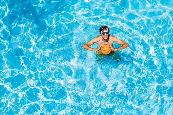 Homem jogar na piscina com uma bola de praia — Fotografia de Stock