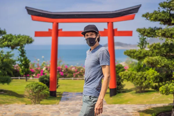 Viajante em máscara médica parou na rua e olhando para o edifício tradicional japonês. Turistas viajam no Japão após a epidemia de coronavírus — Fotografia de Stock