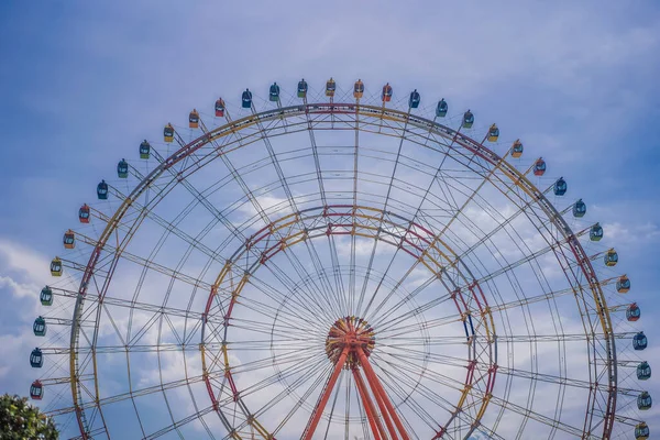 Uma roda gigante com cabines coloridas em uma feira de diversão local — Fotografia de Stock