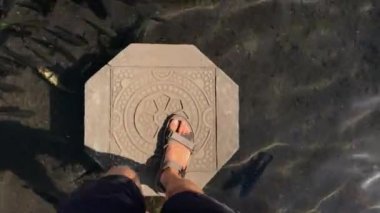 Adam, Bali adasındaki Tirta Gangga sarayında balıklarla dolu bir gölette yürüyor. Telefonla vurulmuş.