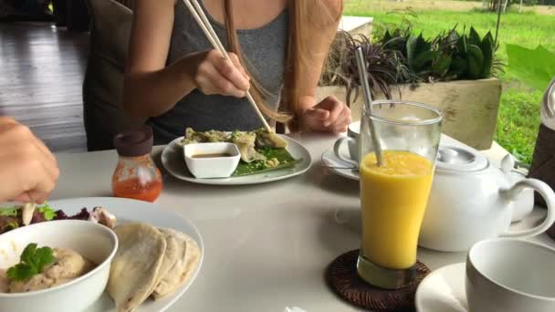 De familie heeft een heerlijke maaltijd in een café met uitzicht op een groen rijstveld. Reis naar Bali concept. Neergeschoten op een telefoon — Stockvideo