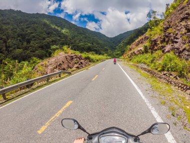 Bulutlu bir havada, yılanlı bir yolda motosiklet sürüyor. Vietnam, Dalat