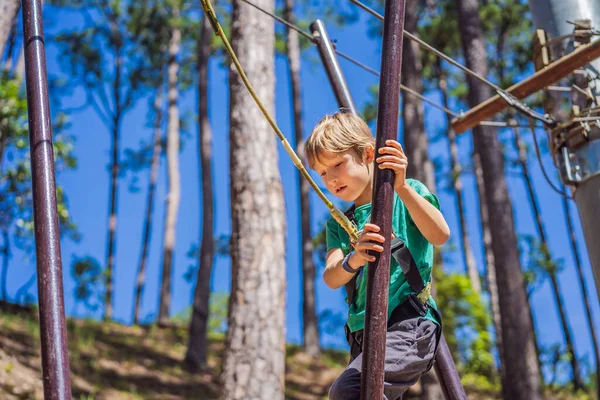 Retrato de menino bonito caminhar em uma ponte de corda em um parque de corda de aventura — Fotografia de Stock