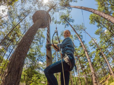 Macera halat parkında güvenlik ekipmanlarıyla genç çekici bir kadın.