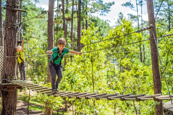 Retrato de niño lindo caminar en un puente de cuerda en un parque de cuerda de aventura — Foto de Stock