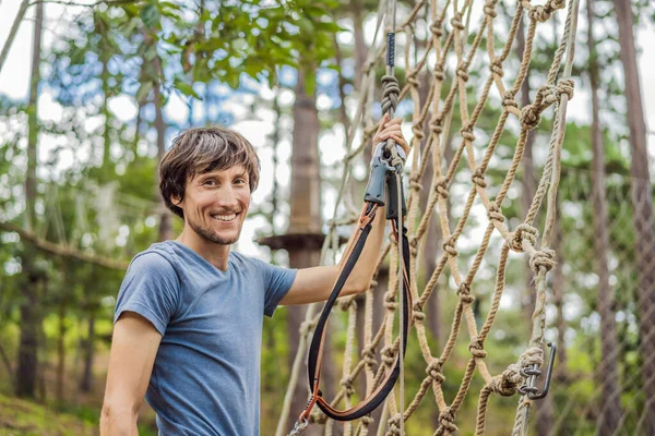 Giovane uomo attraente in parco corda avventura in attrezzature di sicurezza — Foto Stock