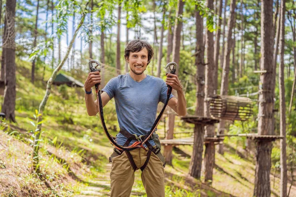 Giovane uomo attraente in parco corda avventura in attrezzature di sicurezza — Foto Stock