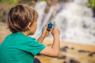 Küçük fotoğrafçı oyuncak kamerayla fotoğraf çekiyor.