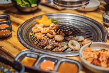 Kadın kömür ızgarasında ızgara yapıyor. Kore ya da Japon geleneksel yemek ızgarası.