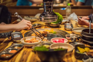 Kadın kömür ızgarasında ızgara yapıyor. Kore ya da Japon geleneksel yemek ızgarası.