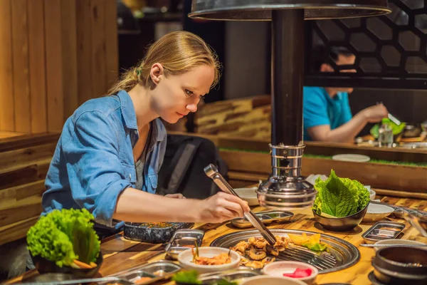 Женщина жарит барбекю на гриле из древесного угля. Корейские или японские традиционные блюда гриль стиль барбекю — стоковое фото
