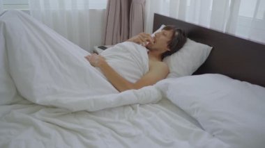 Yatakta yatan genç bir adam uyumadan önce diş koruyucusunu takar. Öğütme Karşıtı Diş Koruyucusu kavramı