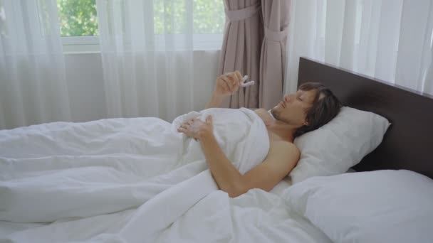 Mladý muž v posteli si před spaním nasadí chrániče zubů. Ochrana proti broušení zubů koncept — Stock video