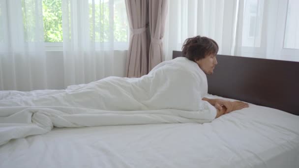En frisk ung man i en säng mår bra efter att ha sovit utan kudde — Stockvideo