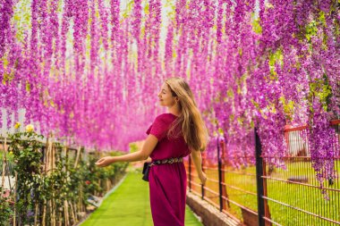 Pembe çiçeklerin arasında sarkan güzel genç bir kadın