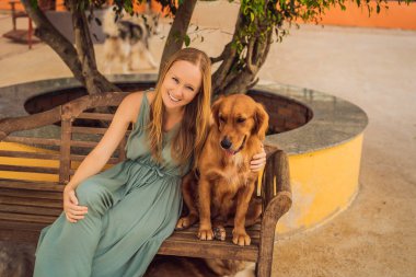 Genç bir kadın sevimli tüylü bir köpeği okşuyor.