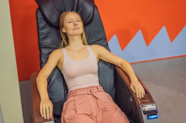 Güzel genç bir kadın havaalanında ya da alışveriş merkezinde masaj koltuğunda dinleniyor.