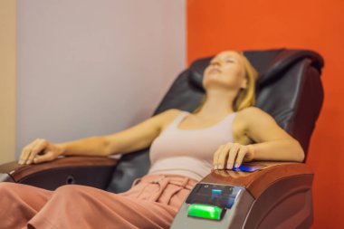 Güzel genç bir kadın havaalanında ya da alışveriş merkezinde masaj koltuğunda dinleniyor.