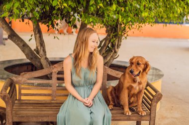 Genç bir kadın sevimli tüylü bir köpeği okşuyor.