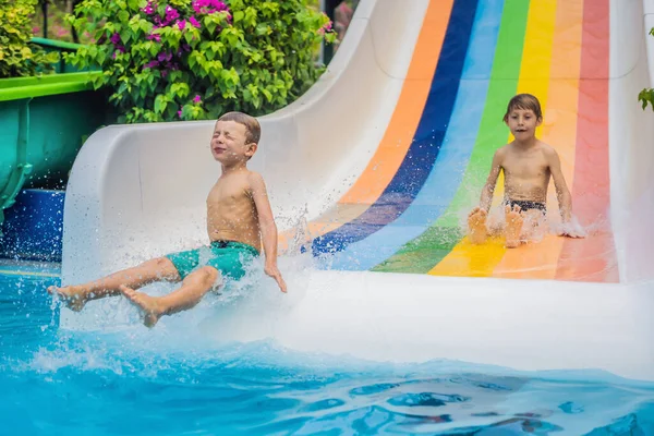 Küçük bir çocuk yaz boyunca su kaydırağına girdikten sonra havuza atlarken eğleniyor. — Stok fotoğraf