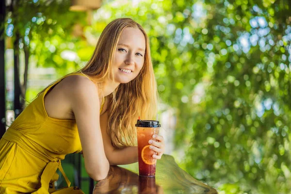 Молодая женщина пьет летний фруктовый напиток на летней террасе — стоковое фото