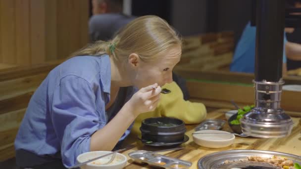 La familia visita un restaurante de parrilla coreano donde se puede cocinar su propia comida. Viajes a Corea concepto — Vídeos de Stock