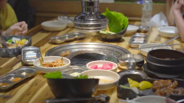 Familjen besöker en koreansk grillrestaurang där du kan laga din egen mat. Resor till Korea-konceptet — Stockvideo