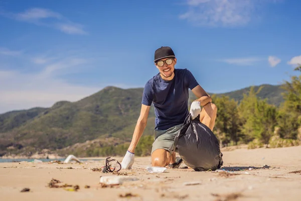 Eldivenli adam denizi kirleten plastik torbalar alıyor. İnsan yapımı kirlilik ve çevresel kirliliğin yol açtığı kumsala çöp dökme sorunu, konsept olarak gönüllü temizleme kampanyası