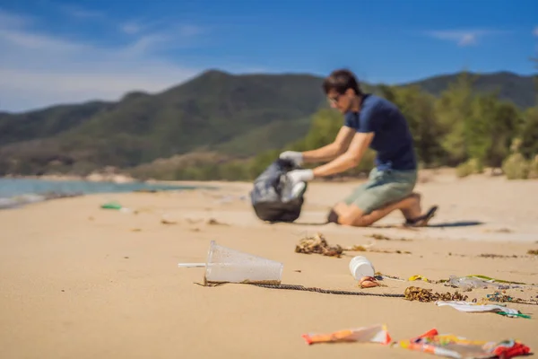 Mann in Handschuhen sammelt Plastiktüten auf, die das Meer verschmutzen. Problem des verschütteten Mülls Müll am Strand Sand durch menschengemachte Verschmutzung und Umweltverschmutzung verursacht, Kampagne zur freiwilligen Reinigung in Konzept — Stockfoto