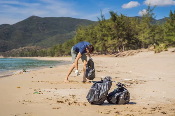 Man in gloves pick up plastic bags that pollute sea. Problem of spilled rubbish trash garbage on the beach sand caused by man-made pollution and environmental, campaign to clean volunteer in concept