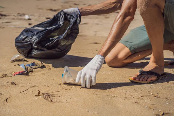 Mann in Handschuhen sammelt Plastiktüten auf, die das Meer verschmutzen. Problem des verschütteten Mülls Müll am Strand Sand durch menschengemachte Verschmutzung und Umweltverschmutzung verursacht, Kampagne zur freiwilligen Reinigung in Konzept — Stockfoto