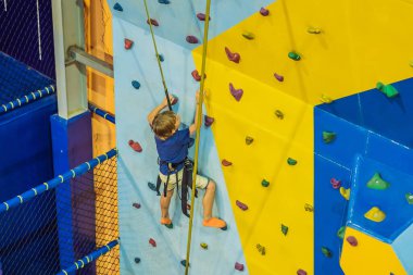 6 yaşında bir çocuk tırmanma merkezinde duvara tırmanıyor.